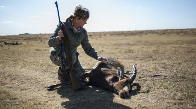 Adri Kitshoff, chief executive officer of Professional Hunters' Association of South Africa (PHASA), kneels by an antelope she hunted at the Iwamanzi Game Reserve in Koster on June 6, 2015/afp