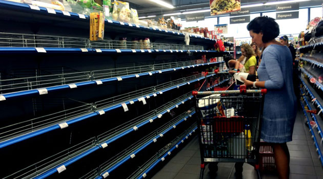 Shoppers stand in an aisle with empty shelves in a supermarket in Athens on July 4, 2015/AFP