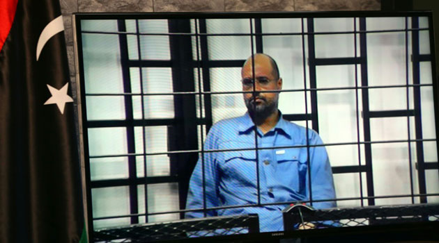 Journalists watch as the judges (unseen), question Seif al-Islam, the son of slain Libyan dictator Moamer Kadhafi, broadcasted live from the western city of Zintan, from inside a room in Tripoli on June 22, 2014/AFP