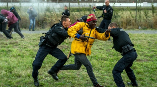 French police try to stop migrants on the Eurotunnel site in Coquelles near Calais, northern France, on July 29, 2015/AFP  