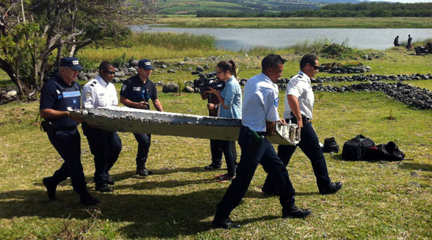 Police carry a piece of debris from an unidentified aircraft found on the Saint-Andre region of the Indian Ocean island of La Reunion, on July 29, 2015/AFP