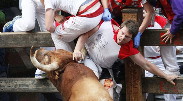 A participant is hurled up against a barrier by a Miura bull after being gored in the thigh during the last bull-run of the San Fermin Festival in Pamplona, northern Spain on July 14, 2014/AFP