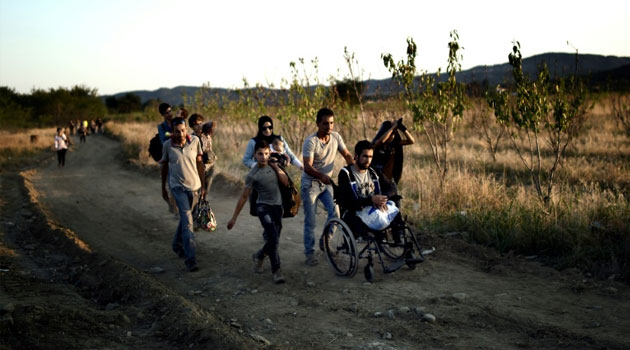 A Syrian man who lost his legs after shelling near Damascus is helped by other migrants after crossing the border from Greece to Macedonia on August 29, 2015/FILE