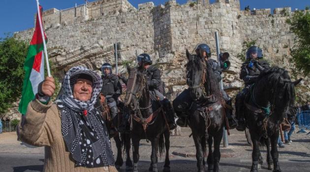 File picture shows a woman waving a Palestinian flag in front of Israeli police outside Damascus Gate in Jerusalem's old city/AFP