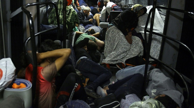 Refugees sleep on a bus as they are transported from Budapest to the Hungarian border village of Hegyeshalom, early on September 5, 2015/AFP