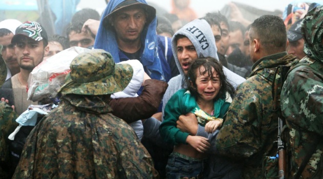 Migrants in the rain to cross the Greek-Macedonian border near the village of Idomeni, in northern Greece on September 10, 2015/AFP  