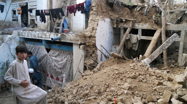 A Pakistani boy stands on the rubble of houses after an earthquake in Kohat on October 26, 2015  © AFP