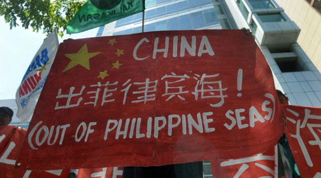 Filipino environmental activists display placards during a rally outside China's consular office in Manila on May 11, 2015 against China's reclamation and construction activities on islands and reefs in the Spratly Group of the South China Sea/AFP