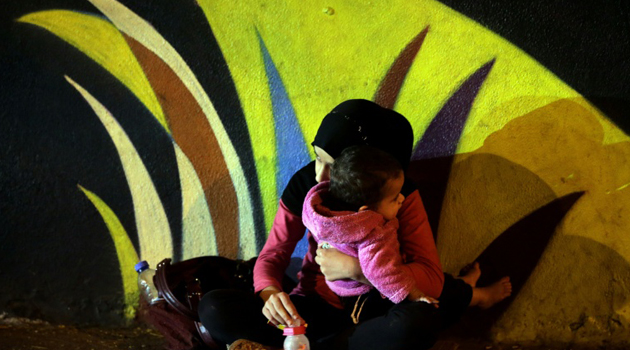 A Syrian refugee girl, carrying a baby/AFP