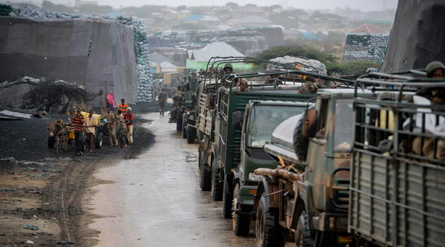 Somali youths pull donkey-drawn water carts past sacks of charcoal as a convoy of the Kenyan Contingent serving with the African Union Mission in Somalia (AMISOM) makes its way through the city of Kismayo. AU-UN IST PHOTO