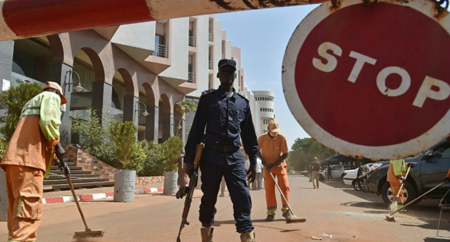 A Malian police officer stands guard as municipal workers clean outside the Radisson Blu hotel in Bamako/AFP