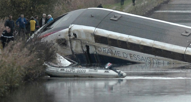 Rescuers work at the scene where a high-speed TGV train coach and engine carriage lie in a canal in Eckwersheim/AFP