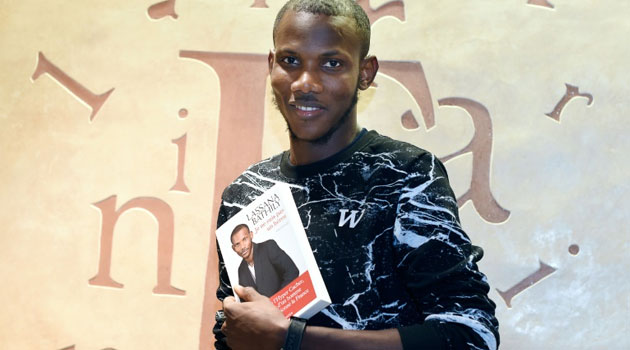 Lassana Bathily, the employee of the Hyper Cacher jewish supermarket in Paris who helped shoppers hide from an islamist gunman who attacked the store on January 9, 2015, poses with book 'Je ne suis pas un heros' ('I Am Not A Hero')/AFP