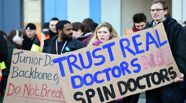 Demonstrators stand with placards outside Salford Royal Hospital in Manchester, northwest England, during a 24-hour strike over pay and conditions on February 10, 2016  © AFP