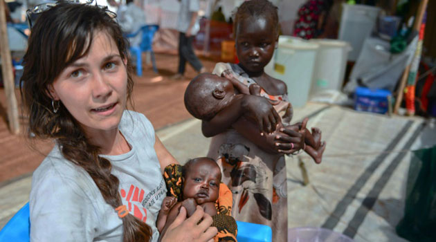 A Medecins Sans Frontieres (MSF) worker holds a baby while two little girls wait for treatment at the MSF hospital in Juba, South Sudan on February 22, 2014/AFP