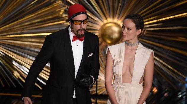 Actor Sacha Baron Cohen (L) and Olivia Wilde speak on stage at the 88th Oscars /AFP