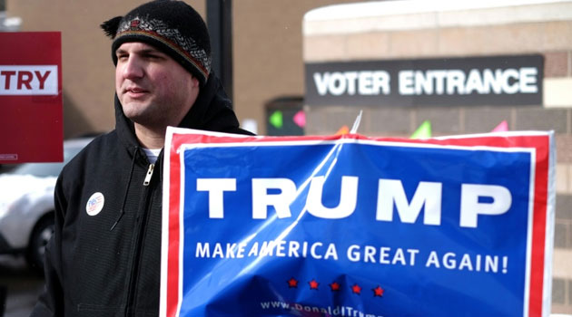 A supporter of US Republican presidential candidate Donald Trump displays a campaign poster as residents vote for the first US presidential primary at a school gym in Concord, New Hampshire, on February 9, 2016/AFP