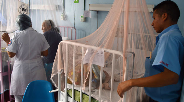 A man looks at a patient covered by a mosquito net in a hospital in El Salvador, on Feb 3, 2016/XINHUA-File