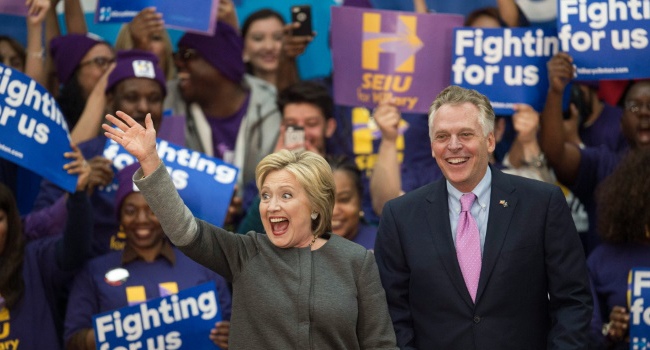 Democratic presidential hopeful Hillary Clinton (L) waves to the crowd/AFP