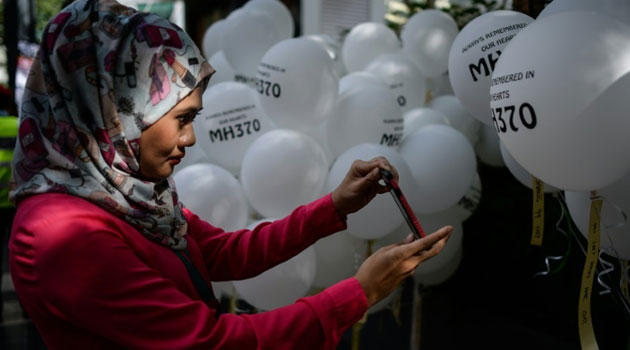 A woman takes pictures of balloons with names of the missing Malaysia Airlines ill-fated flight MH370 during a memorial event in Kuala Lumpur on March 6, 2016/AFP