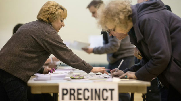 A poll worker instructs voters at a polling station in Warren, Michigan, March 8, 2016/AFP