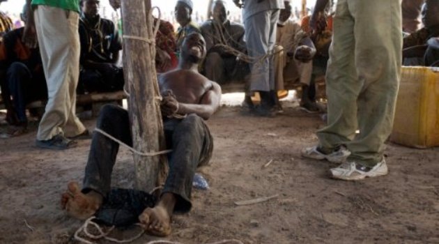 A man suspected of robbery grimaces as he receives lashes from a member of a vigilante group in Kokologo, Burkina Faso/AFP