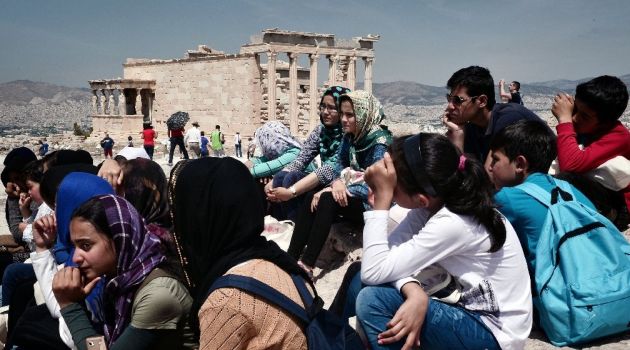 Refugee children from refugee centers in Eleonas and Schisto listen to a guide atop the Acropolis archaeological site in Athens on May 9, 2016/AFP