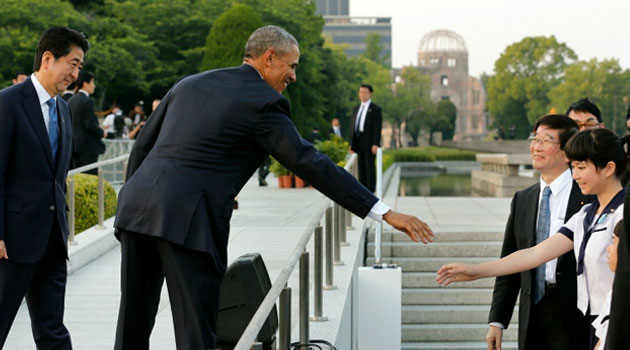 US President Barack Obama (C) greets a school student as Japanese Prime Minister Shinzo Abe watches (L) after laying wreaths for victims of the atomic bombing in 1945, at Hiroshima Peace Memorial Park/AFP