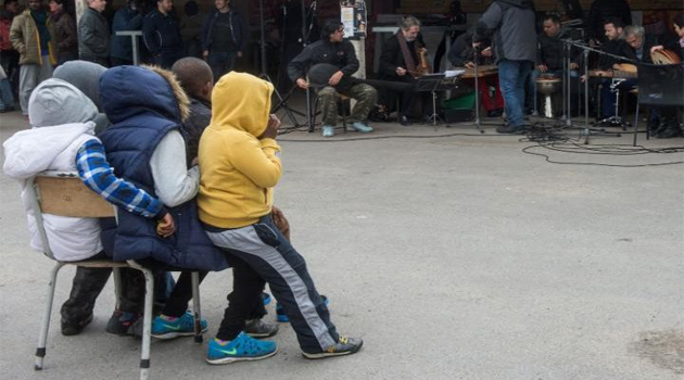 Children listen to musicians perform at the Jules Ferry migrants support center in Calais, France/AFP