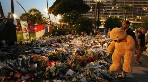 A man holds a giant teddy bear in front of a makeshift memorial near the Promenade des Anglais in Nice/AFP