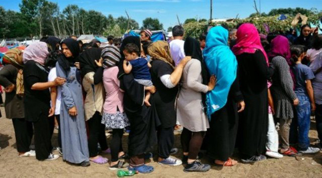 Women queue to receive food at a migrant camp situated on the Serbia-Hungary border in Horgos on July 8, 2016/AFP