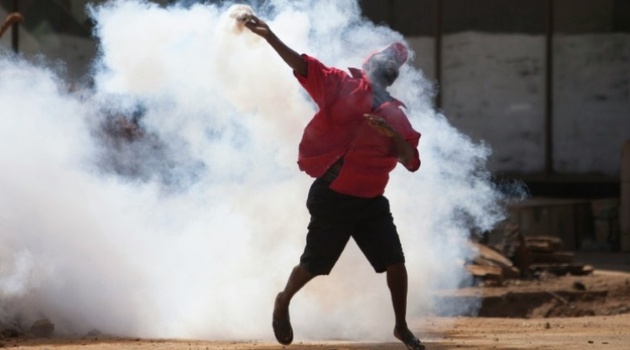  A supporter of the Zimbabwe opposition party Movement for Democratic Change Tsvangirai faction (MDC-T) throws back a tear gas canister during clashes with police in Harare on August 24, 2016/AFP-File