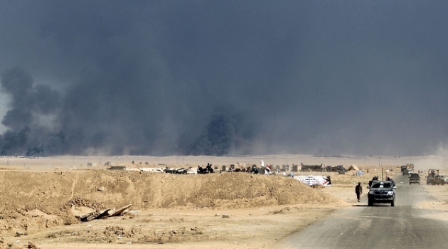 Smoke billowing on the horizon as Iraqi forces gather at Qayyarah military base about 60km south of Mosul/AFP