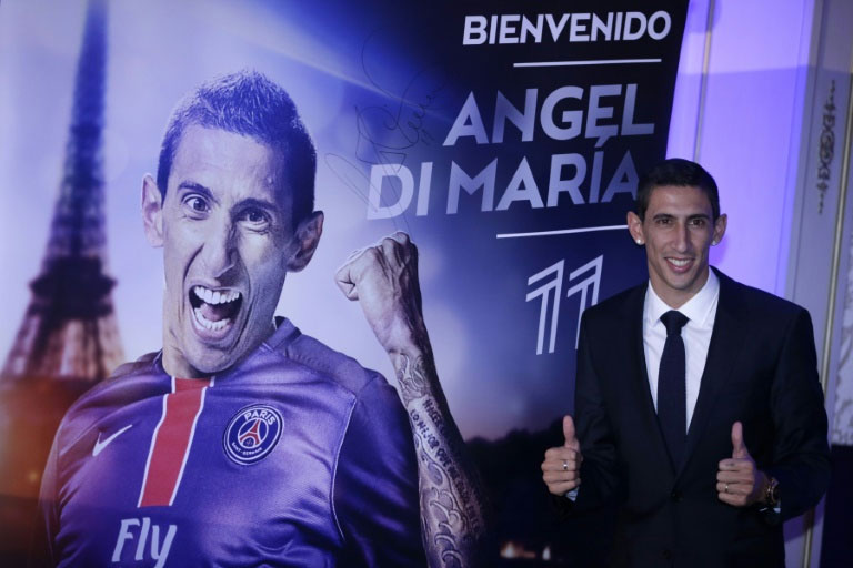 PSG midfielder Angel Di Maria flashes two thumbs up as he poses next to a poster during his official presentation in Paris on August 6, 2015. PHOTO/AFP