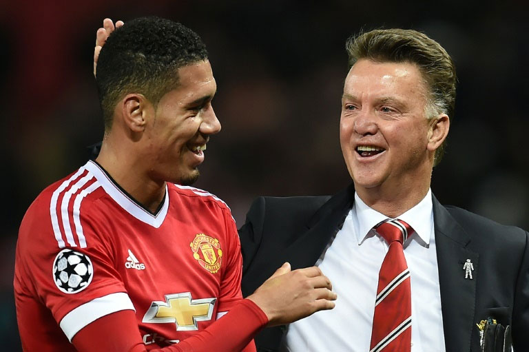 Manchester United manager Louis van Gaal jokes with defender Chris Smalling as they leave the pitch at the end of the Champions League Group B match against Wolfsburg at Old Trafford on September 30, 2015. PHOTO/AFP