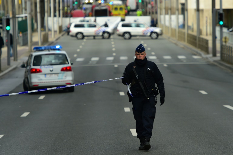 A police officer sets up a security cordon near Maalbeek metro station in Brussels on March 22, 2016 after a blast at thie station near the EU institutions caused deaths and injuries. PHOTO/AFP.